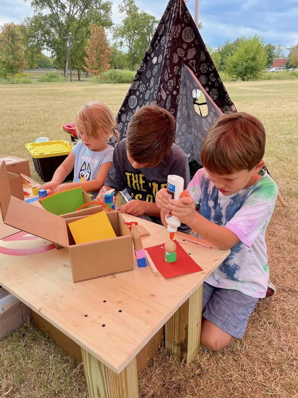 Kids creating outdoors next to a starry tent